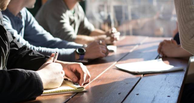 Mensen die notities nemen aan een houten tafel